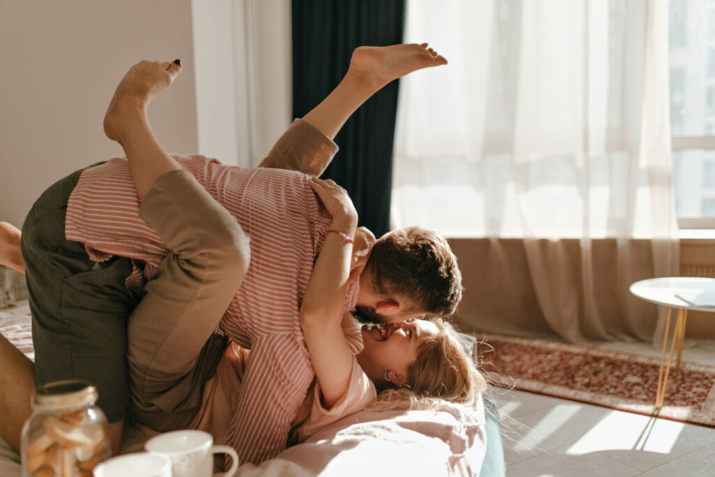 Couple living together and playing on their sofa while asking questions to ask before moving in together