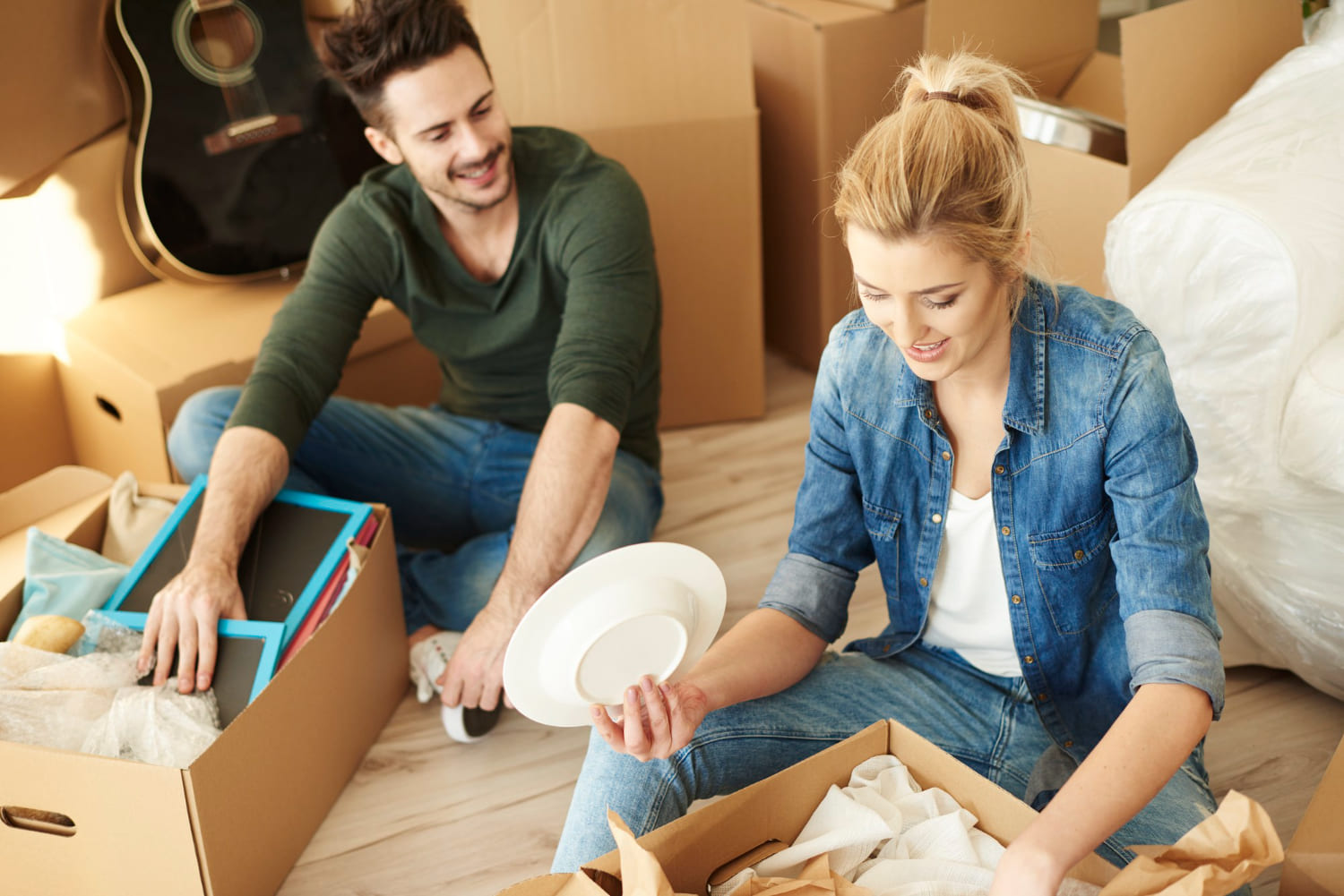 21 Questions to Ask Before Moving in Together as a Couple Couple unpacking boxes together in their new apartment