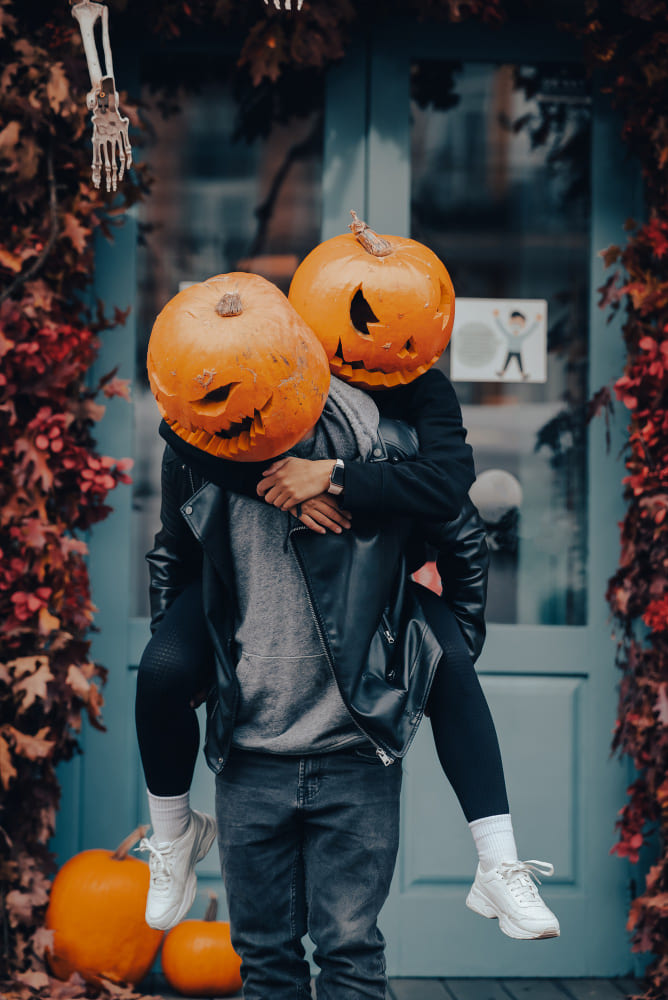 Couple in matching Halloween (Pumpkin heads) outfits enjoying a themed party